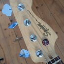 Fotografie zachycuje hlavu světlého dřevěného basového nástroje s chromovanými ladičkami. Na dřevě je vidět nápis Squier BY FENDER a PRECISION BASS®.…