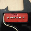 Červený snímač s šesti póly osazený v černém plastovém rámu. Na horní části je bílá nálepka s nápisem TUMA pickups a webovou adresou www.tumapickups.…