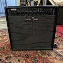 Černý kytarový kombozesilovač s texturovaným povrchem a černou přední síťovkou. Na horním ovládacím panelu je nápis HB-40MFX 40W GUITAR AMP a logo Ha…
