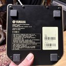 Zadní strana černého efektového procesoru značky YAMAHA. Na přístroji je nápis ACOUSTIC EFFECTS PROCESSOR, MODEL UB99A a AC POWER ADAPTOR: YAMAHA AC-…