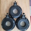 Tři černé kruhové elektronické padů z plastu. Každý pad má nápis „Roland“ na horním držáku a štítek s textem „PDX-8 Mesh TOM PAD“. Povrchy jsou v dob…