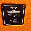Detail zadní strany kytarového cabinetu s oranžovým povrchem. Na černém plastovém štítku je bílý nápis ORANGE VOICE OF THE WORLD, Serial No: PPC412-1…