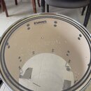 Fotografie znázorňuje snare drum s průhledným membránou. Na membráně je viditelné logo EVANS a označení EC25. Povrch membrány vykazuje známky opotřeb…