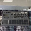 Šedý sampler/sekvencer značky KORG s nápisem electribe MUSIC PRODUCTION STATION. Zařízení obsahuje několik otočných potenciometrů, digitální displej…
