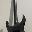 Zadní strana elektrické kytary v černé barvě s lesklým povrchem. Na hlavě nástroje je vidět nápis "Custom Shop" a pod ním menší, nečitelný text. V tě…