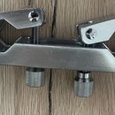 Kovové svorky na hmatník nástroje v stříbrné barvě. Předmět obsahuje dvě stahovací šrouby s motýlkovými hlavami a dva spodní nastavovací knoflíky. Po…