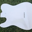 Bílá pickguard pro elektrickou kytaru v typickém tvaru Telecastera. Povrch je hladký a lesklý, s vyvrtanými otvory pro montáž a šesti otvory pro sním…