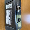 Záběr na spodní stranu černého efekt pedálu s kovovým šasi. Na bílém štítku je uveden nápis tc electronic, DESIGNED IN DENMARK a údaje 9V DC/100mA. D…