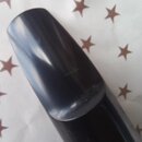 Detailní pohled na černý, lesklý mouthpiece z plastu nebo ebonitu. Na povrchu nejsou vidět žádné značky, loga ani nápisy. Povrch vykazuje drobné neči…