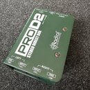 Zelená stereo DI box s kovovým povrchem. Na horní straně je bílý nápis PROD2 STEREO DIRECT BOX, logo Radial engineering a text Made in Canada. Na pře…