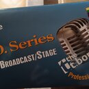 Modrá krabice s obrázkem stříbrného mikrofonu v retro stylu. Na krabici jsou nápisy „the Ut.bone“, „PRO. Series“ a „STUDIO/BROADCAST/STAGE“. V pravém…