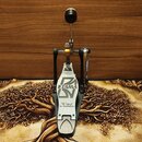Fotografie znázorňuje basový pedál v kovovém provedení s černými a stříbrnými prvky. Na šlapce je vidět logo TAMA a nápis The Legend in Innovation. P…