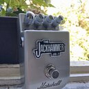 Stříbrný efekt pedál s kovovým povrchem. Na přední straně je nápis THE JACKHAMMER JH-1 a ve spodní části logo Marshall. V horní části jsou čtyři kovo…