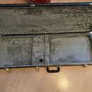 Otevřený obdélníkový kufřík s černým vnějším povrchem a šedou plišovou výplní. Kufřík má kovové zapínání a černou plastovou rukojeť. Na vnitřní stran…