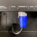 Detail zadní strany černého hudebního zařízení s několika konektory. Na horní liště jsou nápisy POWER, MAINS IN 100-240 VAC~50-60Hz, PEDAL, SPEAKER O…
