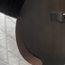 Detailní pohled na černý povrch akustického nástroje. Na hraně je vidět přisazení dřevěného ochranného krytu (pickguard) s viditnou strukturou zrna.…