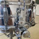 Detailní pohled na chromovaný snare drum s kovovým korpusem. Na mechanismu throw-offu je viditelný nápis "Star". Povrch vykazuje známky používání v p…