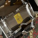 Detailní pohled na chromovaný obrub bubnu s několika kovovými mechanismy. Uprostřed je žlutý štítek s nápisy SONOR SIGNATURE SERIES 50, Made in Germa…