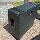 Černý obdélníkový reproduktorový box s povrchem z texturovaného materiálu. Hrany jsou chráněny kovovými profilemi a rohy jsou opatřeny kovovými zpevň…