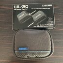 Fotografie zobrazuje krabici od bezdrátového systému s nápisy WL-20 Wireless System, Wireless Freedom Made Easy a For Electric Guitar/Bass with Stand…