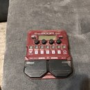 Červený multi-efektový procesor s nápisy B1 FOUR, ZOOM a Multi-Effects Processor. Zařízení má čtyři ovládací knofíky s popisky Lo, Mid, Hi a Vol, pět…