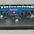 Černý efekt pedál s nápisy TONEBONE, Radial JX-2 PRO a SWITCHBONE. Na horní straně jsou ovládací prvky: dva stisknuté přepínače s popisky BOTH a BOOS…