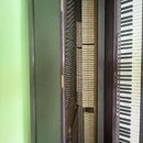 Fotografie zachycuje vnitřní mechanismus pianina s otevřeným horním víkem. Je vidět řada kladiveček, struny a klávesnice s bílými a černými klávesy.…