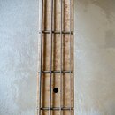 Detail krku basové kytary s hmatníkem zC světlého dřeva s výraznou kresbou (birdseye maple). Nástroj má čtyři struny a kovové pražce. V horní části j…