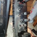 Fotografie zachycuje vnitřní chassis elektronického zařízení, pravděpodobně zesilovače. Na šedém kovovém panelu jsou umístěny dvě elektronky, několik…