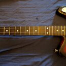 Elektrická kytara s hnedým hmatníkem a bílými tečkovými značkami poloh. Tělo má červeno-černý sunburst povrch a bílý pickguard. Na fotce nejsou žádné…