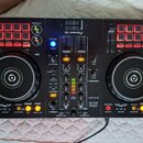Černý DJ kontrolér značky Pioneer DJ, model DDJ-400. Zařízení obsahuje dva jog-wheels, několik červeně podsvícených padů a centrální mixážní sekci s…