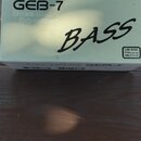 Fotografie znázorňuje bílou papírovou krabici. Na ní je uveden nápis BOSS, model GEB-7 a text Bass Equalizer. V pravé části je šikmý nápis BASS a v p…