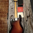 Elektrická basová kytara s trupem v tmavě hnědém sunburst provedení a světle barevným hnedým krčkem. Na hlavě nástroje je viditelné logo Fender. Kyta…