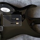 Zadní strana černé elektrické kytary s lesklým povrchem. Na těle je nalepený oválný bílý štítek s nápisy „schecter“, „guitar research“ a „SET UP TO P…