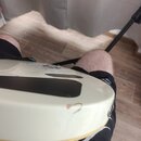 Detail spodní části bílé elektrické kytary. Na hraně korpusu je viditelný odřap a opotřebení laku. V horní části je vidět černý plastový kryt elektro…