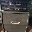 Černý kytarový kombozesilovač značky Randall, model RH300 G3 Plus, s ovládacím panelem obsahujícím několik potenciometrů a přepínačů. Je umístěn na č…