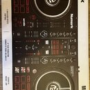 Černý DJ kontrolér značky Numark s modelem MIXTRACK PRO FX. Zařízení má dvě velké jog-kola, červené ovládací tlačítka a v horní části nápis Numark. N…