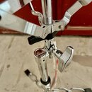 Detail chromovaného stojanu s kovými rameny. Na kulatém prvku v prostřední části je viditelné logo "Pearl". Povrch je lesklý, s viditelnými odlesky a…