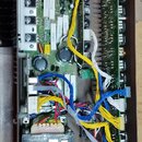 Fotografie zachycuje vnitřek elektronického zařízení s několika plošnými spáči a kabeláží. V dolní části je umístěn černý transformátor s bílým štítk…