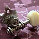 Kovový ladicí mechanismus s bílým, kulatým knoflíkem z plastu nebo kosti. Na kovové části je vyražen nápis GOTOH. Povrch kovu vykazuje známky oxidace…