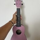 Růžové ukulele s černým hmatníkem a černým mostkem. Na hlavě nástroje je nápis Keiki®. Uvnitř ozvučnice je vidět bílý štítek s nečitelným textem. Nás…