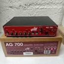 Červený basový zesilovač s černým krytem a nápisy Aguilar a AG 700 Ltd. Přední panel obsahuje řadu ovládacích knoflíků s popisky GAIN, BRIGHT, TREBLE…