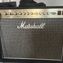 Kytarový kombozesilovač značky Marshall s modelem DSL 40C. Má černý kryt, stříbrný ovládací panel s řadou knoflíků a šedý textilní přední grill. Na p…