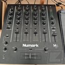 Černý mixážní pult s nápisem Numark a označením M6 USB. Zařízení obsahuje čtyři vstupní kanály (CH1 až CH4) a jeden Master kanál, každý s posuvníkem…