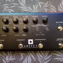 Černý kytarový zesilovač s nápisem AMPED 3 a doplňujícím textem DEPT. 10 | 100W 3 CHANNEL AMP. Na horním panelu se nachází dvanáct ovládacích knoflík…