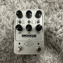 Stříbrný efekt pedál s šesti černými oválnými knoflíky. Na přední straně je nápis KNUCKLES a pod ním text '92 REV F DUAL REC AMPLIFIER spolu s logem…