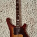 Elektrická basová kytara s trupem v červenohnědém sunburst provedení a černým pickguardem. Na hlavě hmatníku je svisle napsaný nápis TORROU. Nástroj…