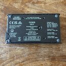 Fotografie zachycuje spodní stranu černého napájecího zdroje pro efektové pedály. Uprostřed je uveden text CIOKS DC7 POWER SUPPLY FOR EFFECT PEDALS V…
