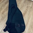 Černý poloměký pouzdro (gig bag) na kytaru s ramenním popruhem. Povrch je vyroben z černé textilie, spodní část obsahuje síťovanou kapsu. Na pouzdře…