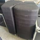 Dvě černé polstrované podložky v podobě vysokých válců s plochou horní stranou. Povrch je z černého syntetického materiálu, který vykazuje známky opo…